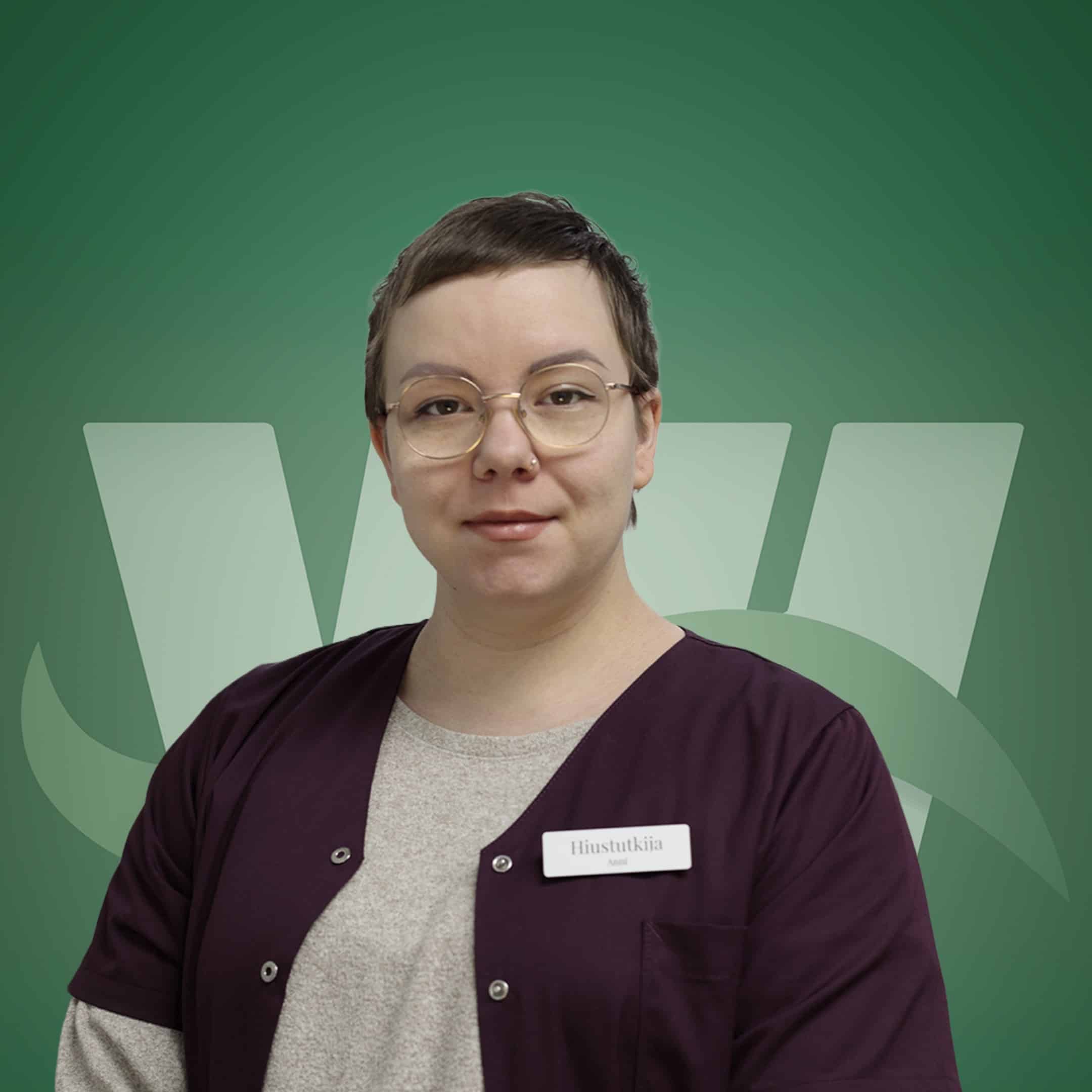Person with short dark hair and round glasses wearing a maroon scrub top over a gray shirt, with a name badge on the chest against a green abstract background.