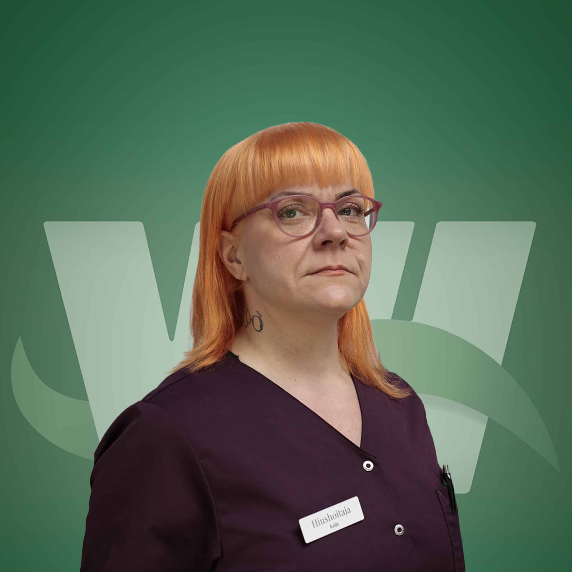 Close-up portrait of a person with orange hair and pink glasses wearing burgundy scrubs, name badge visible against a green background.